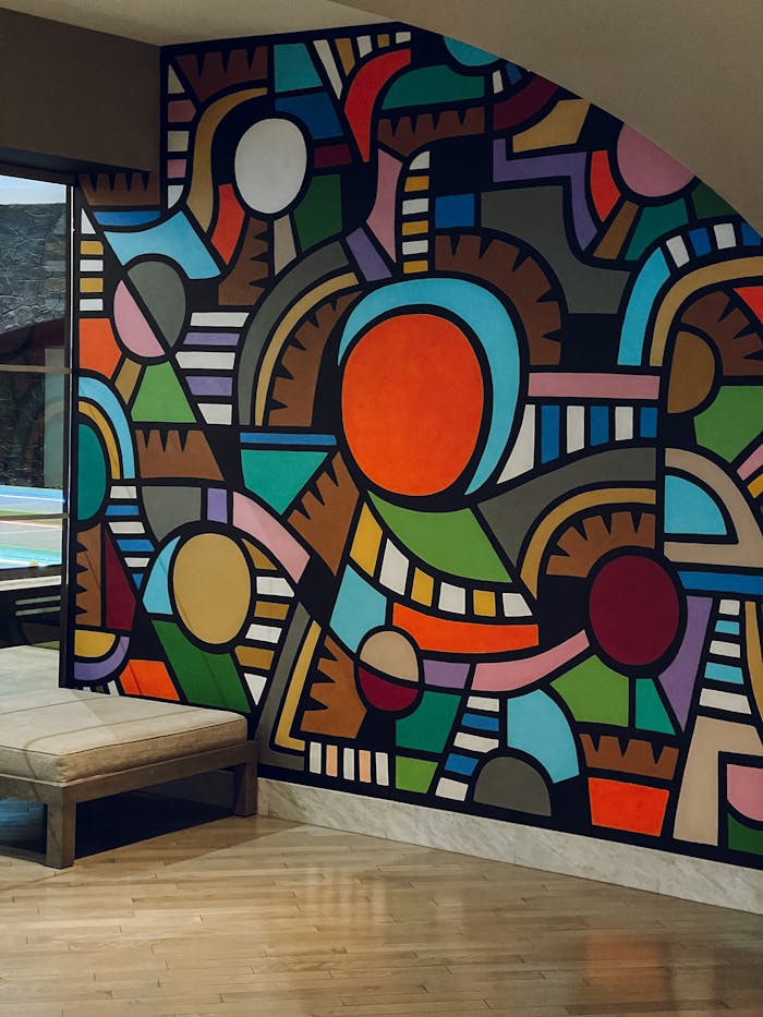 Colorful geometric abstract mural with natural light in an indoor setting.