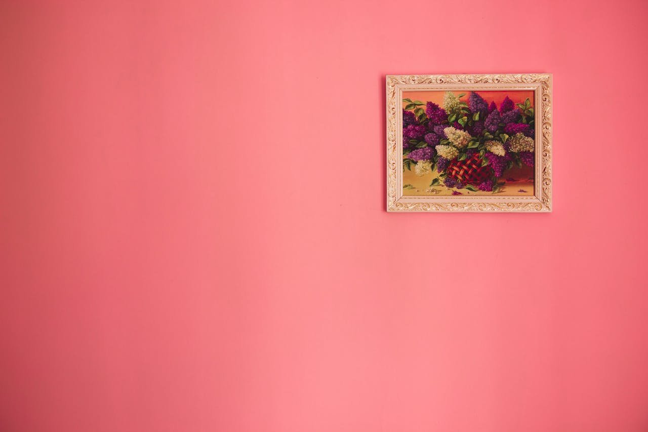 hero-img-02 Bright floral painting in ornate frame against a pink background.
